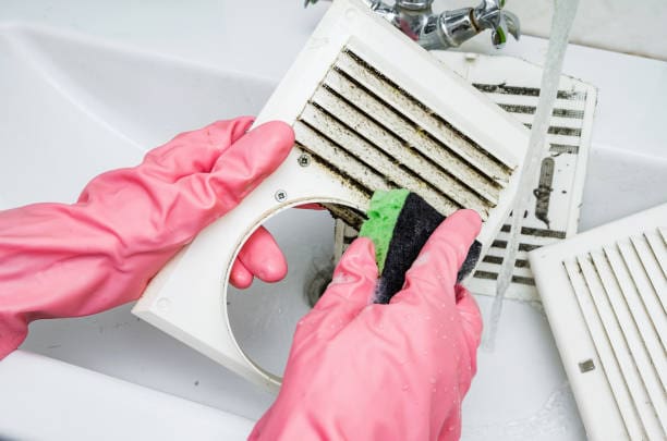 Photo personne nettoyant des grilles d'aération